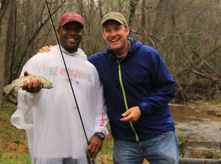 Two participants smiling with a freshly caught trout