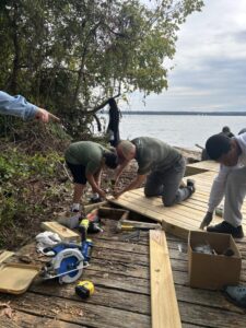 Volunteers cutting and fitting boardwalk boards near the shore